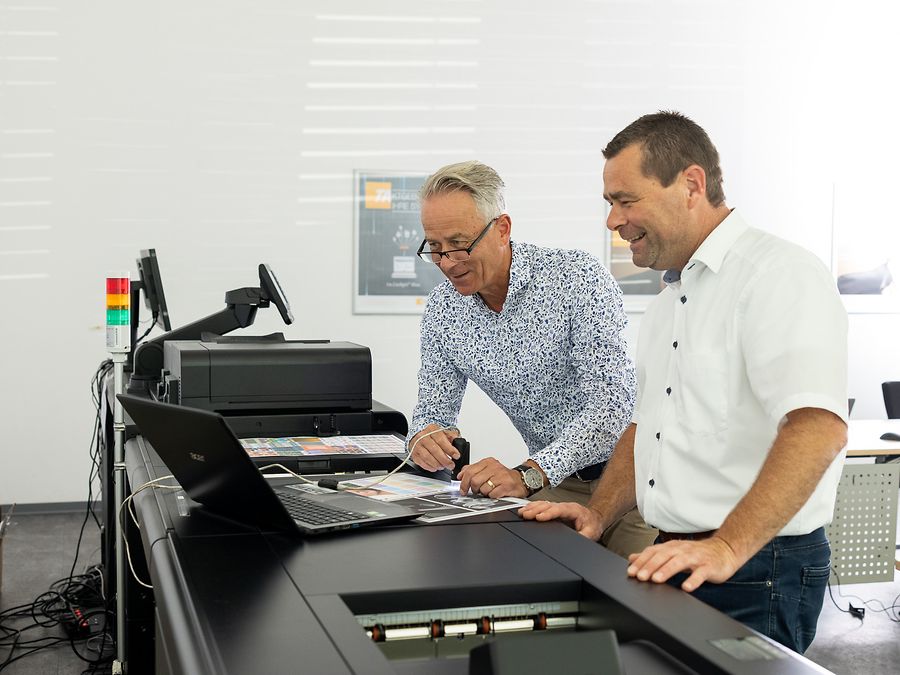 Zwei Männer stehen an der Produktionsdruckmaschine